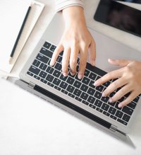 Zwei Hände tippen auf einer Tastatur eines Laptops